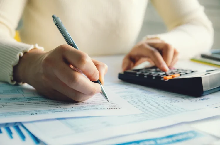 Small business owner reviewing equipment purchase receipts and calculating Section 179 tax deductions with calculator on desk